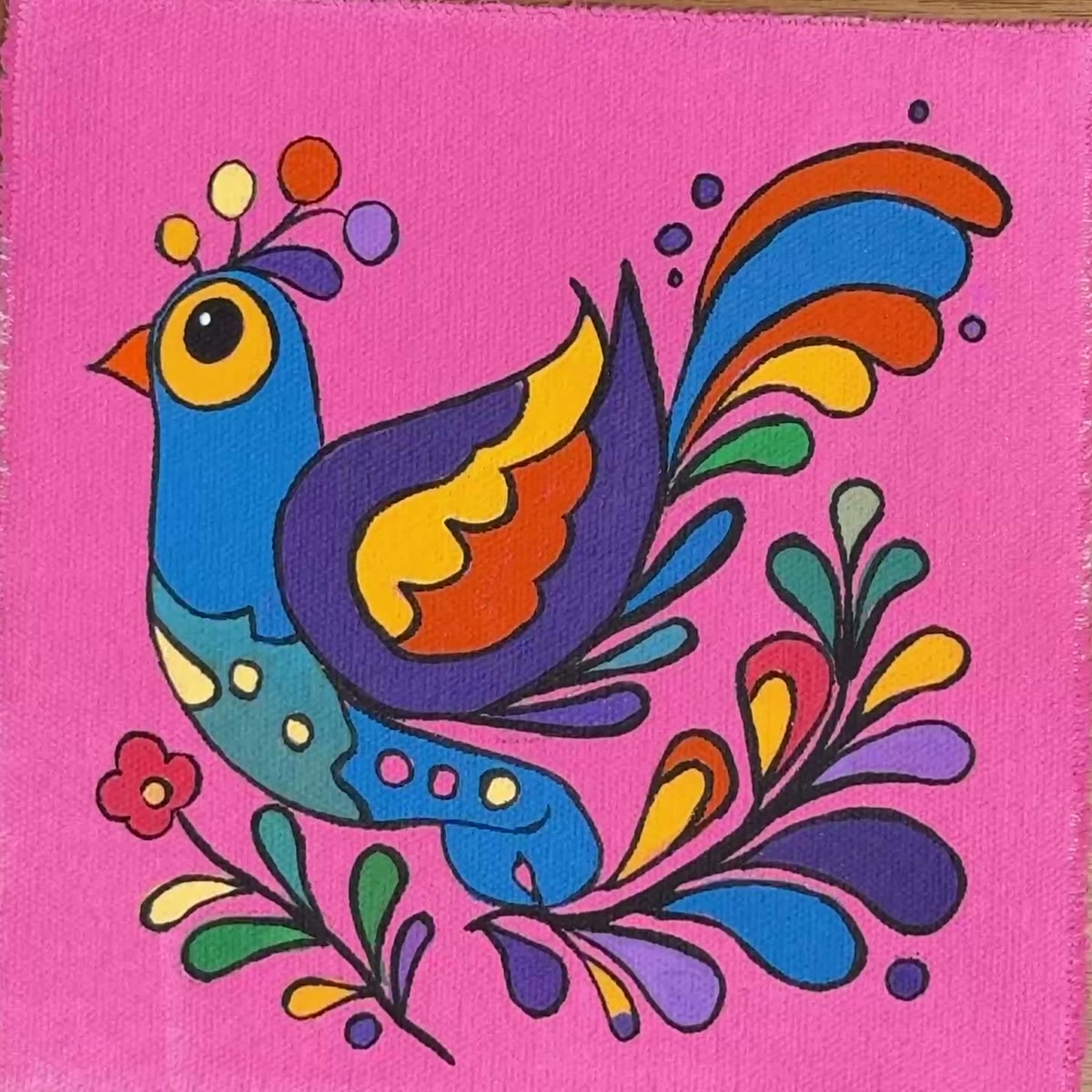 Folk bird with a blue body, purple wing and orange flame feathers on a pink ground